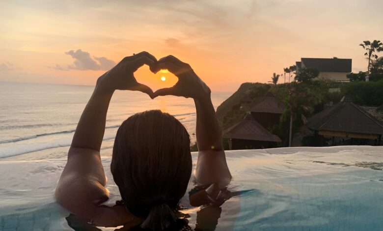 a woman sitting in a pool making a heart with her hands