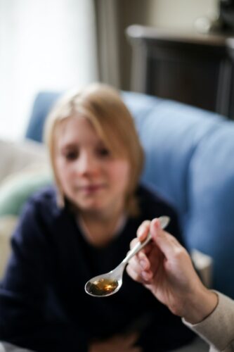A Person Holding a Spoon with Cough Syrup