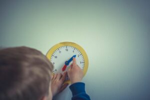 person in blue long sleeve shirt holding white round analog wall clock