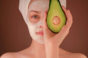 woman with white face mask holding green fruit