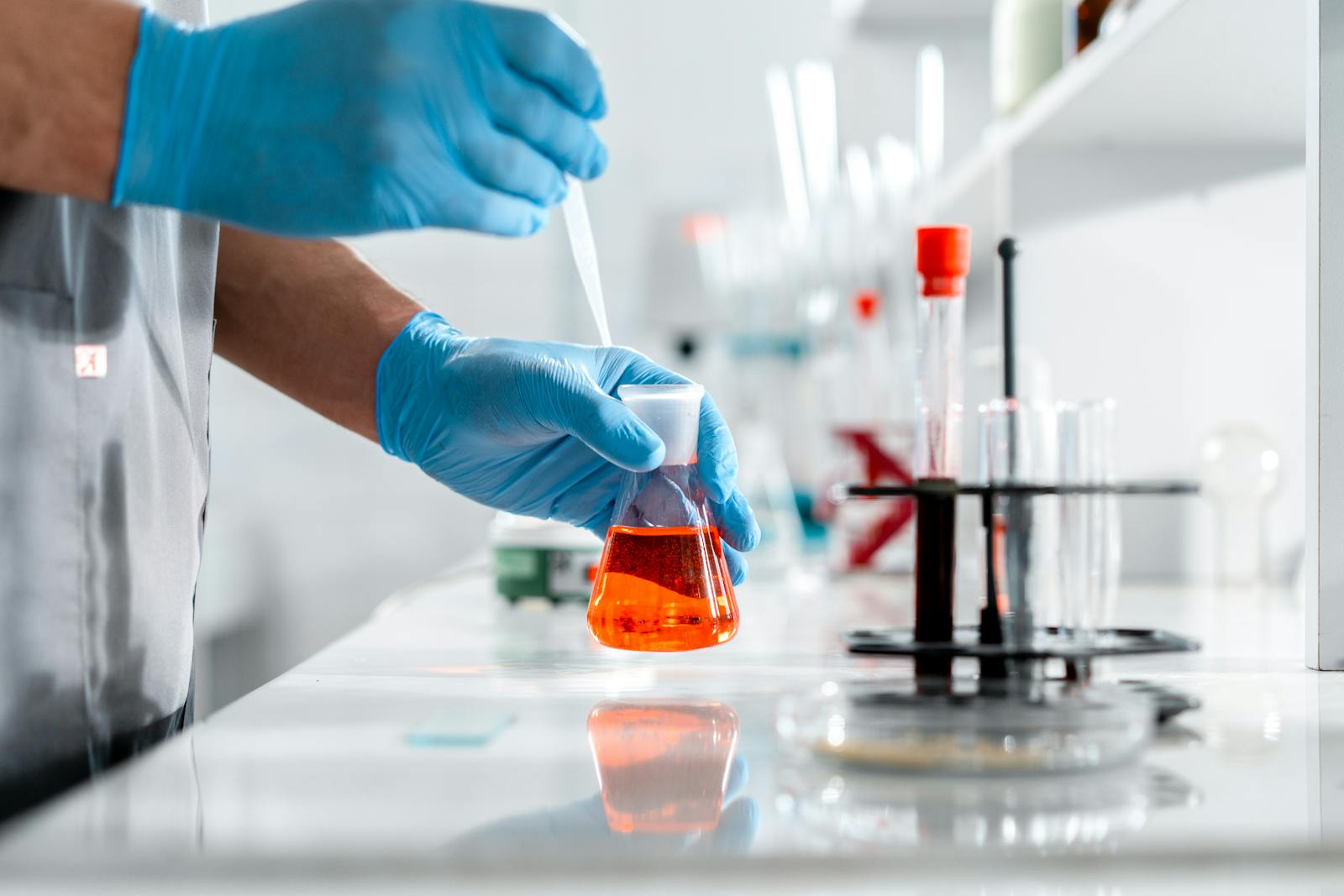 Scienziato in laboratorio con pipetta e beuta di vetro durante un esperimento