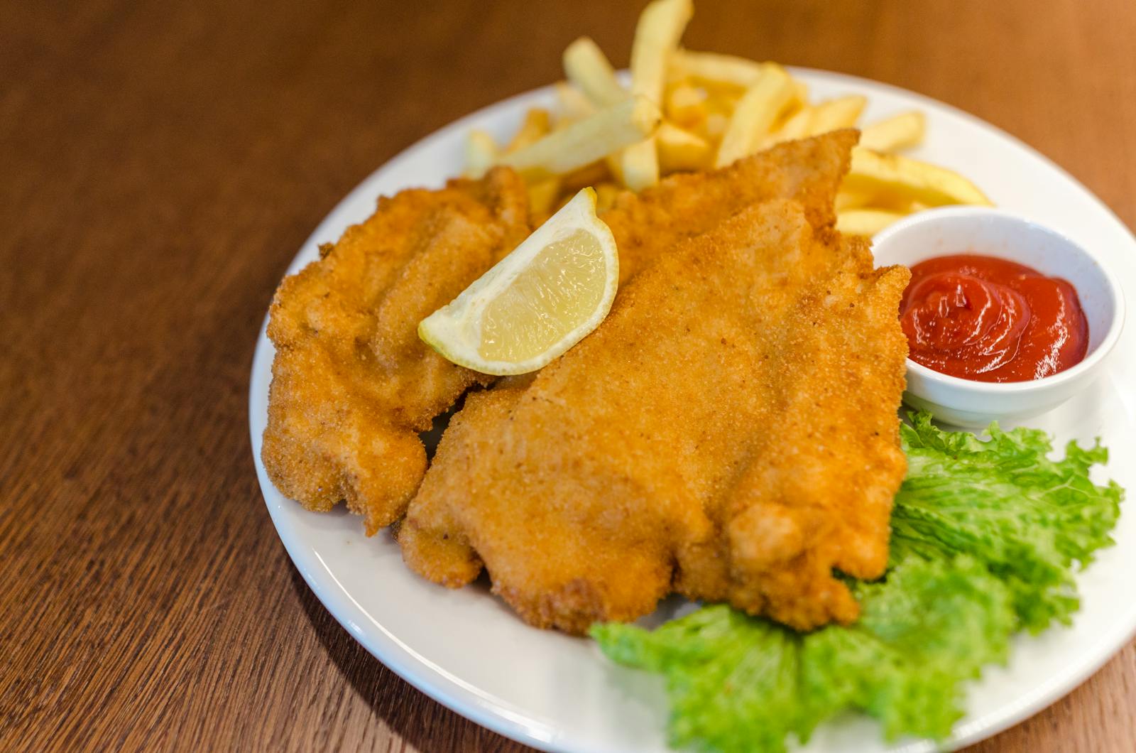 Cotoletta servita con patatine, lattuga e limone, una delle versioni più diffuse