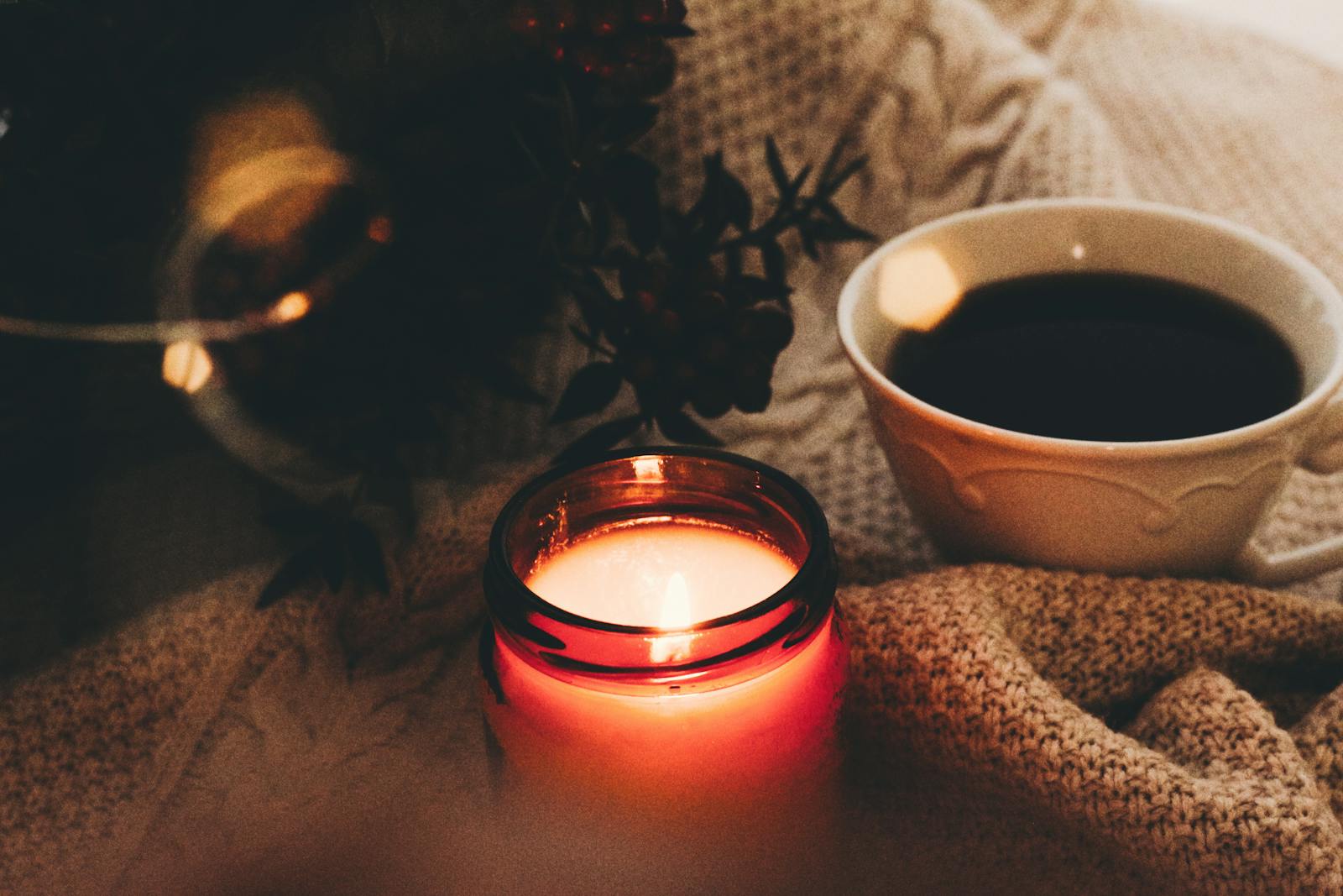 Candela e tazza di caffè su un maglione di lana