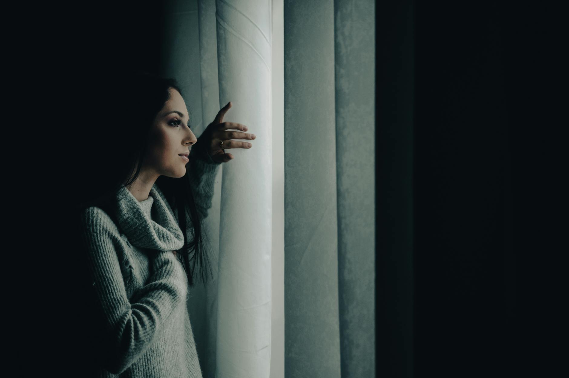 Donna pensierosa che guarda fuori dalla finestra in una giornata invernale
