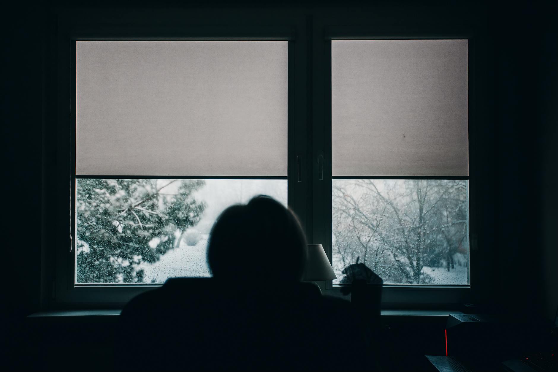 Silhouette di una persona dietro una finestra ghiacciata in inverno