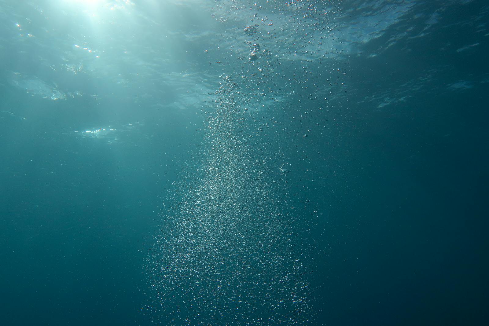 Scena subacquea con luce solare e bolle d'aria nell'oceano