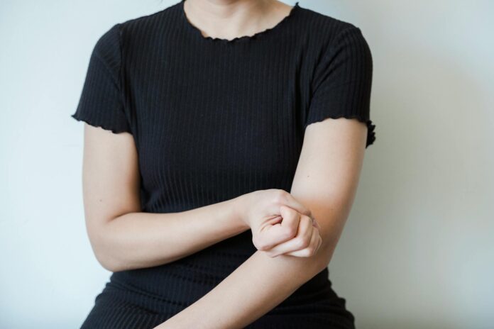 Persona che si tocca la pelle dell'avambraccio