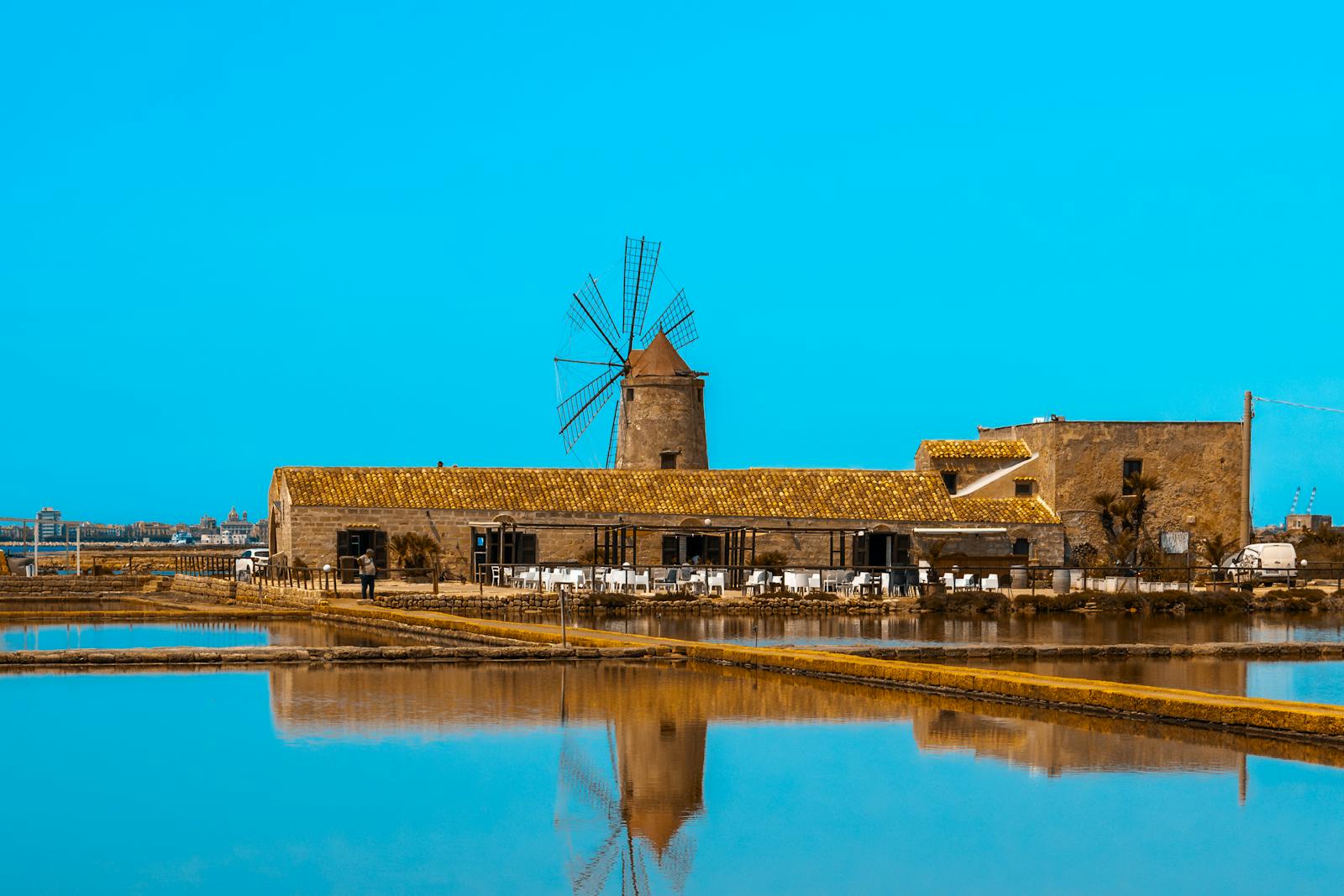 Mulino storico delle saline di Trapani con barche e cielo limpido