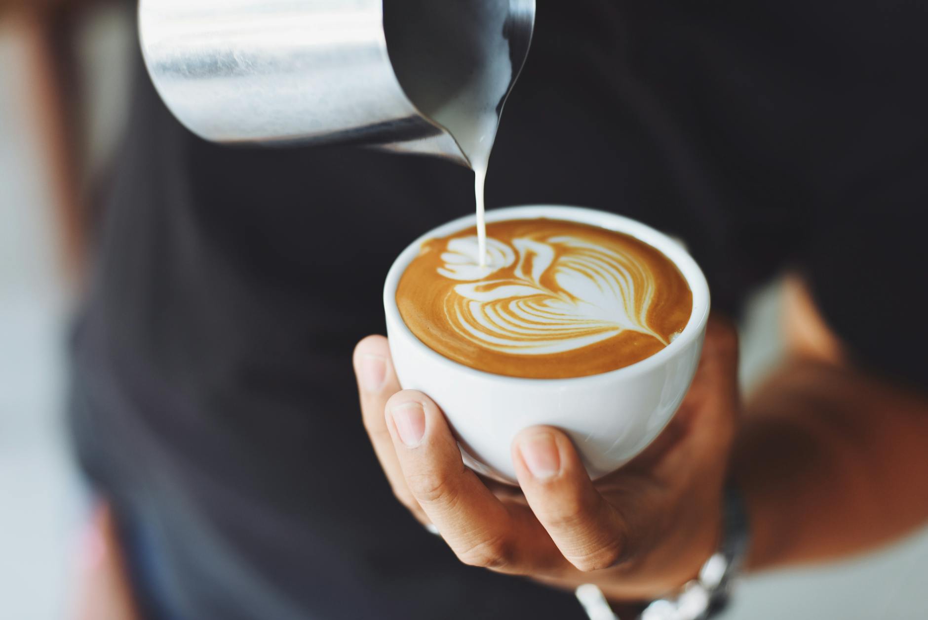 Barista versa il latte montato per creare latte art