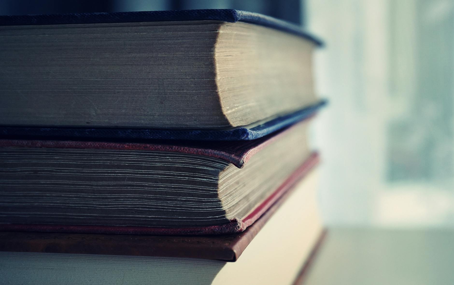 Libro aperto accanto a una pila di volumi