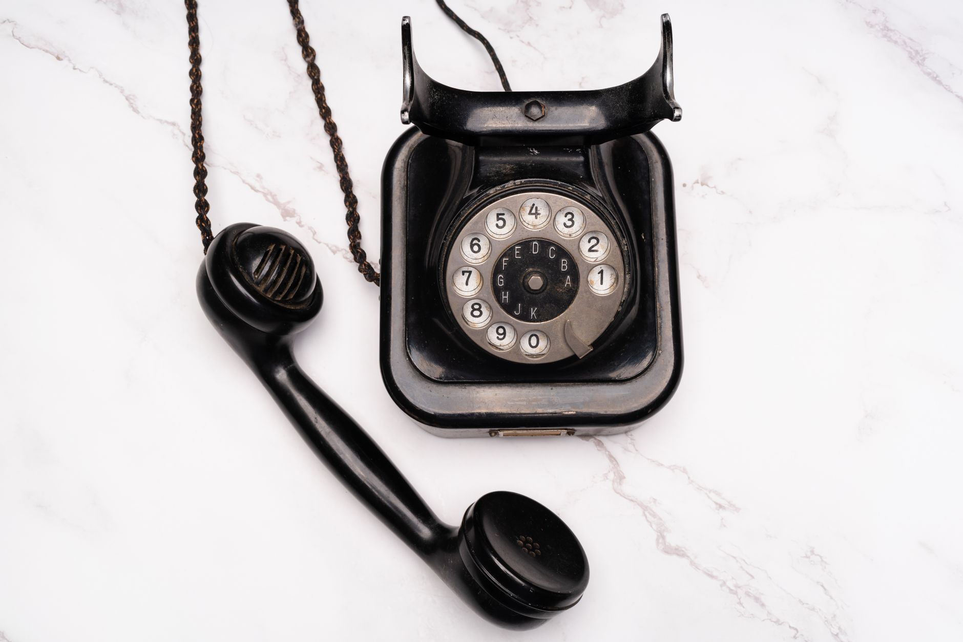 Vecchio telefono nero con disco combinatore su sfondo neutro