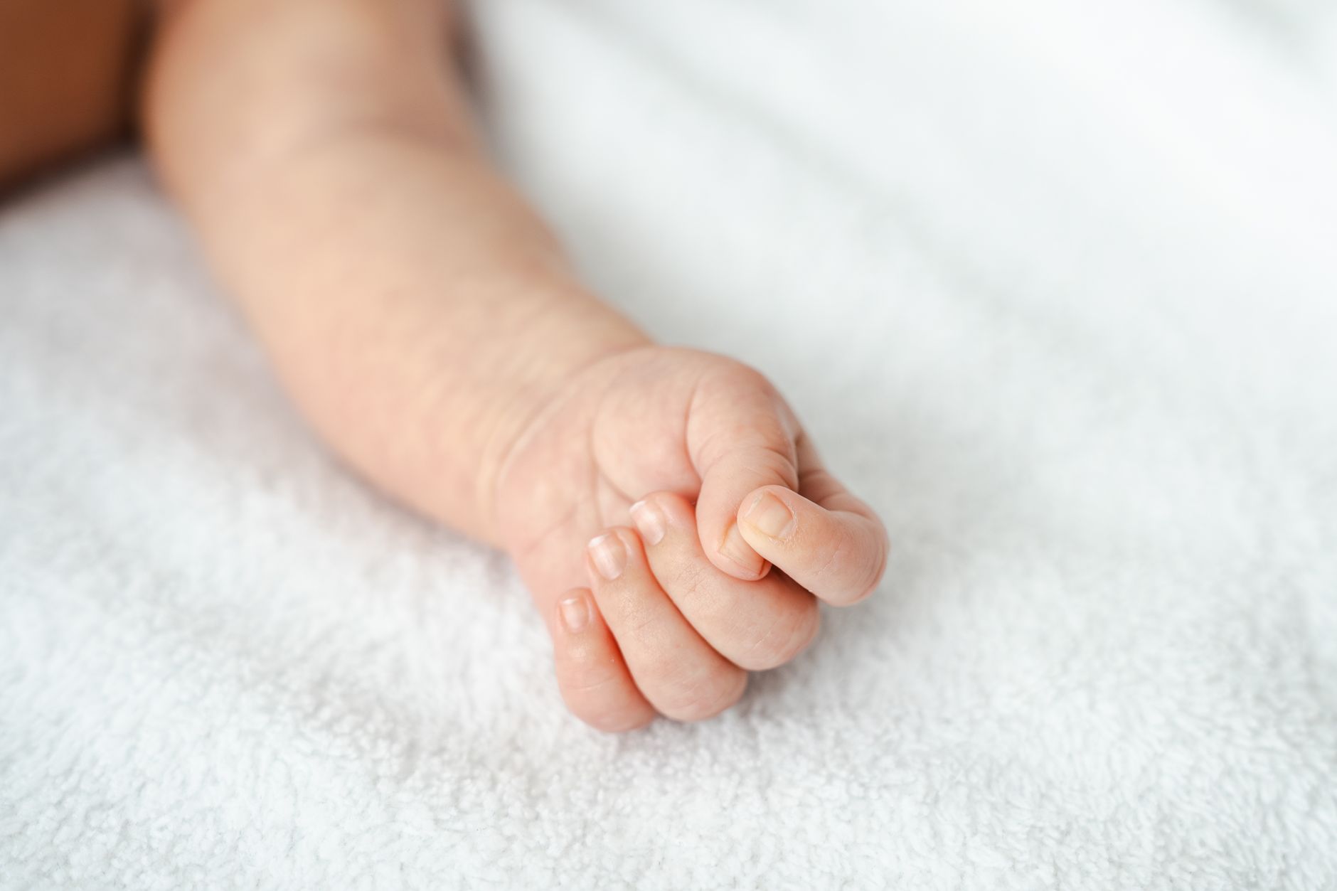 Mano di un neonato stretta intorno al dito di un adulto