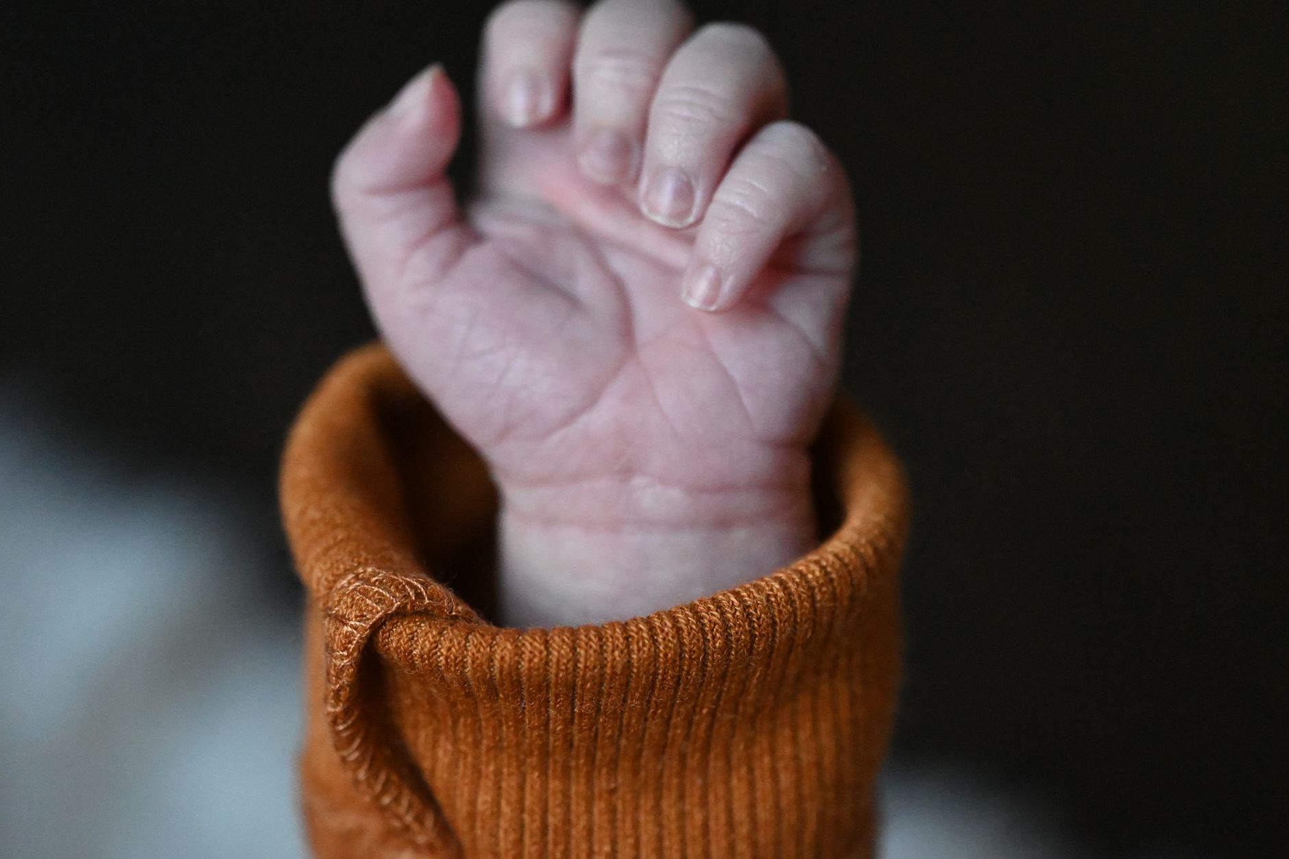 Mani di un adulto che tengono i piedi di un neonato