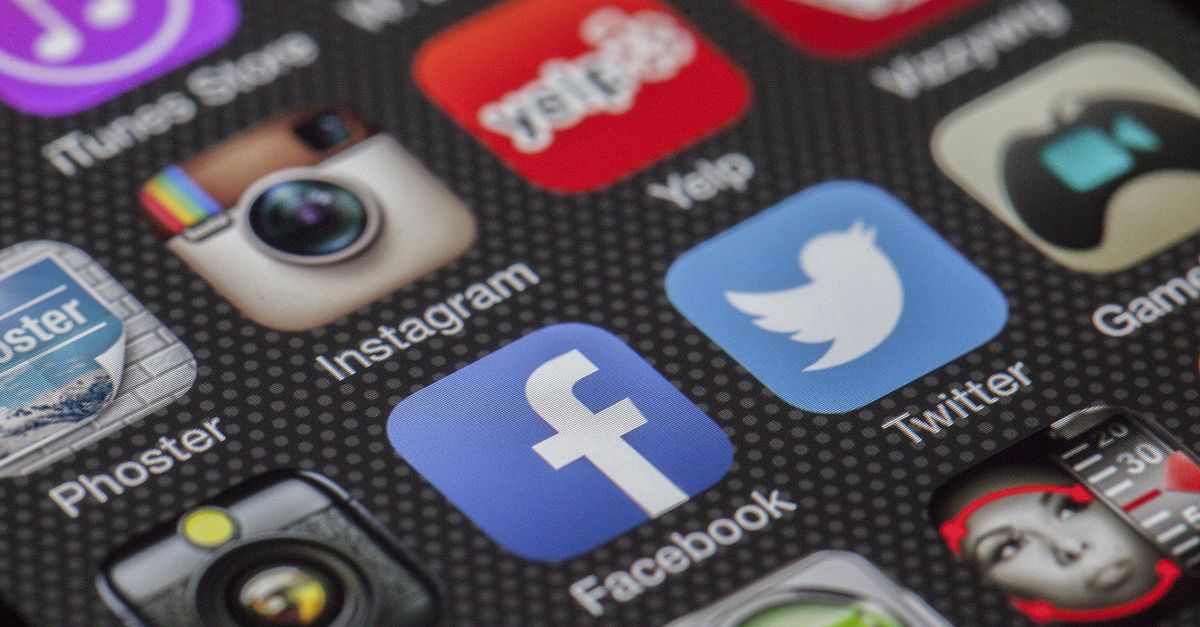 Mano che tiene uno smartphone con applicazioni social