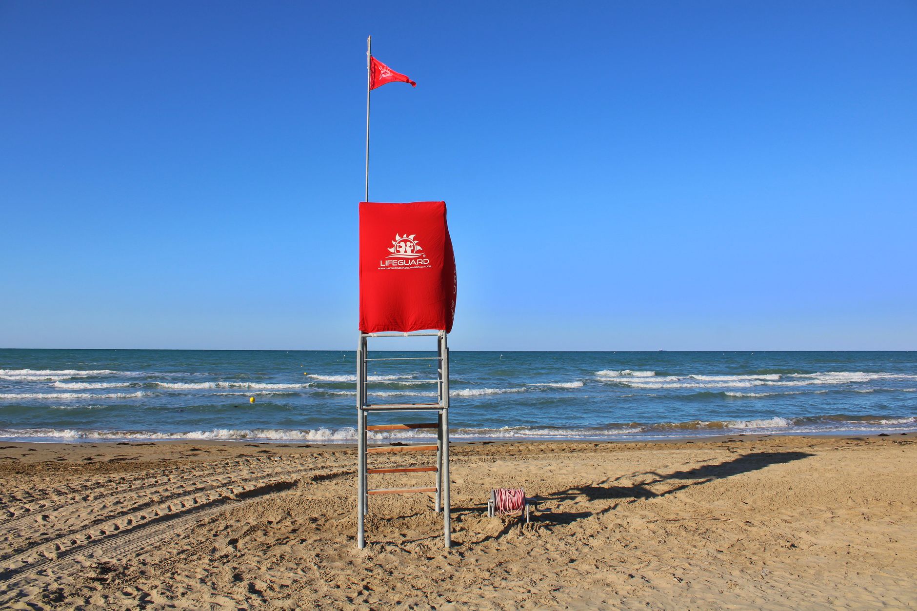 Spiaggia con bagnino di sorveglianza e bandiera di sicurezza in mare