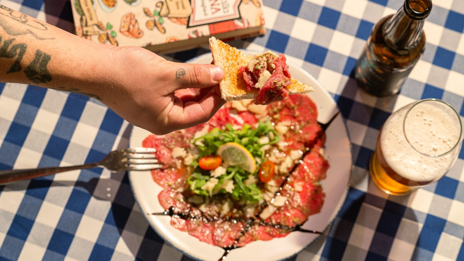 Un piatto di carpaccio di manzo con scaglie di formaggio e rucola