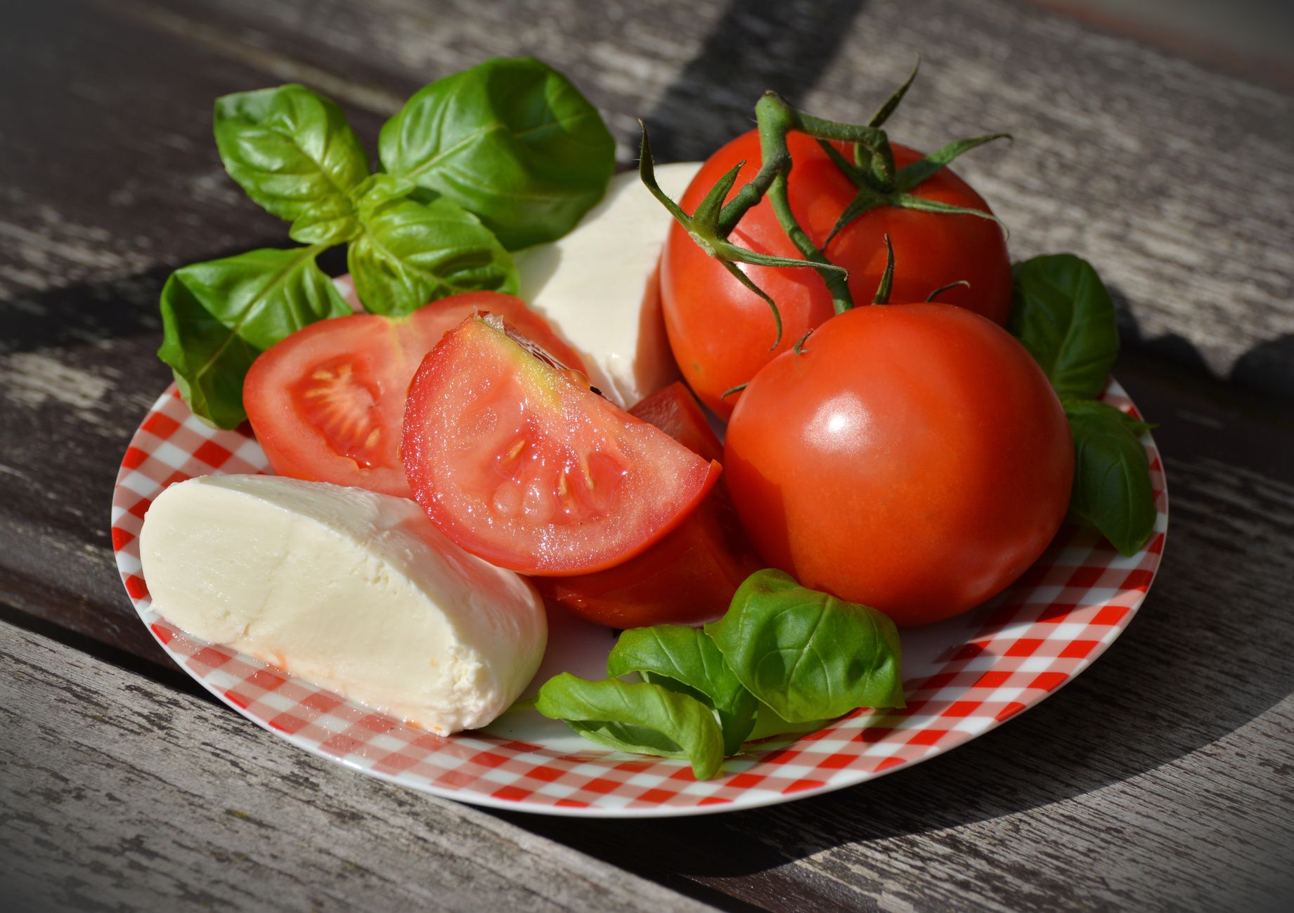 Fette di pomodoro e mozzarella alternate con foglie di basilico