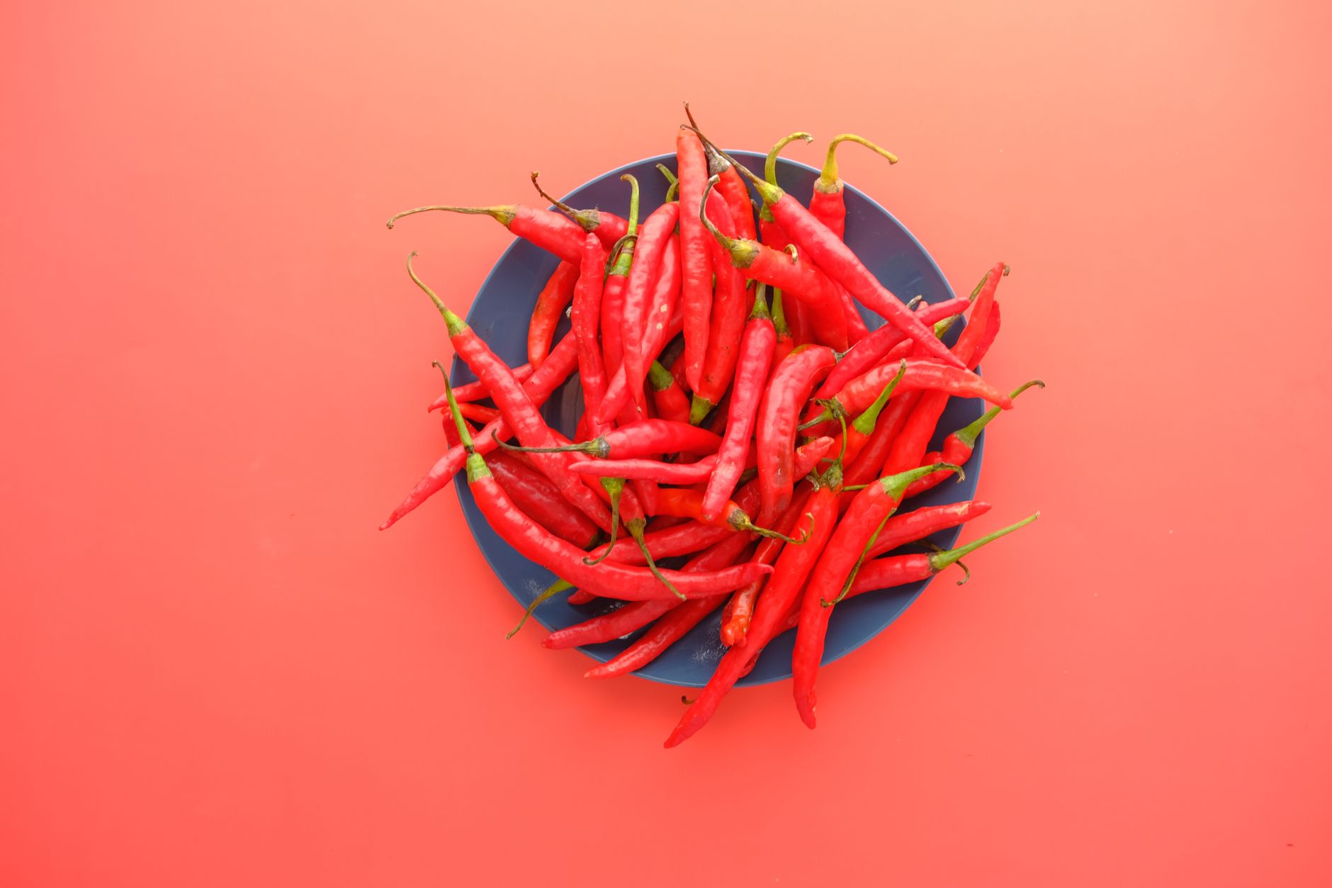 Peperoncini rossi freschi accanto a una boccetta di salsa piccante