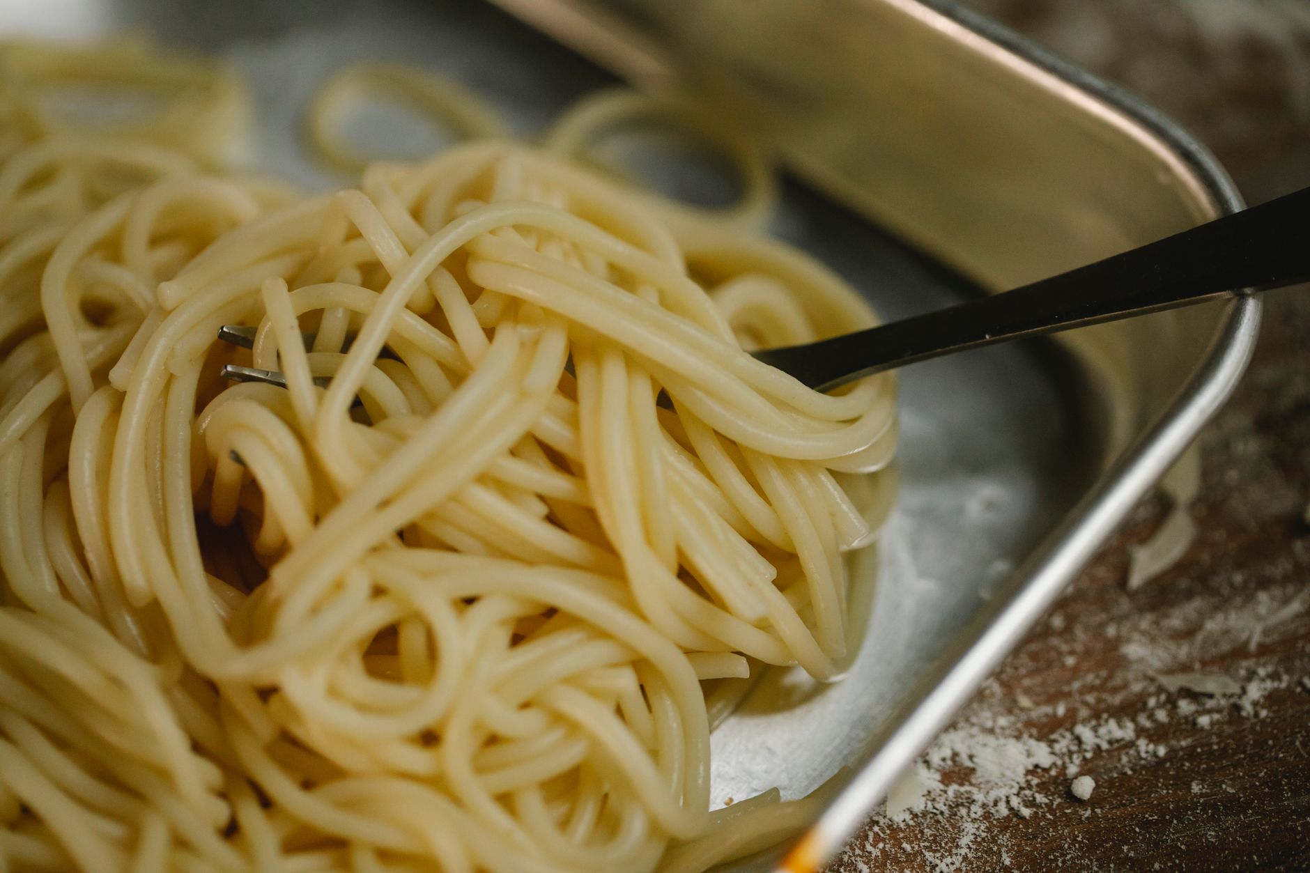 Mani che lavorano la pasta fresca su una spianatoia infarinata