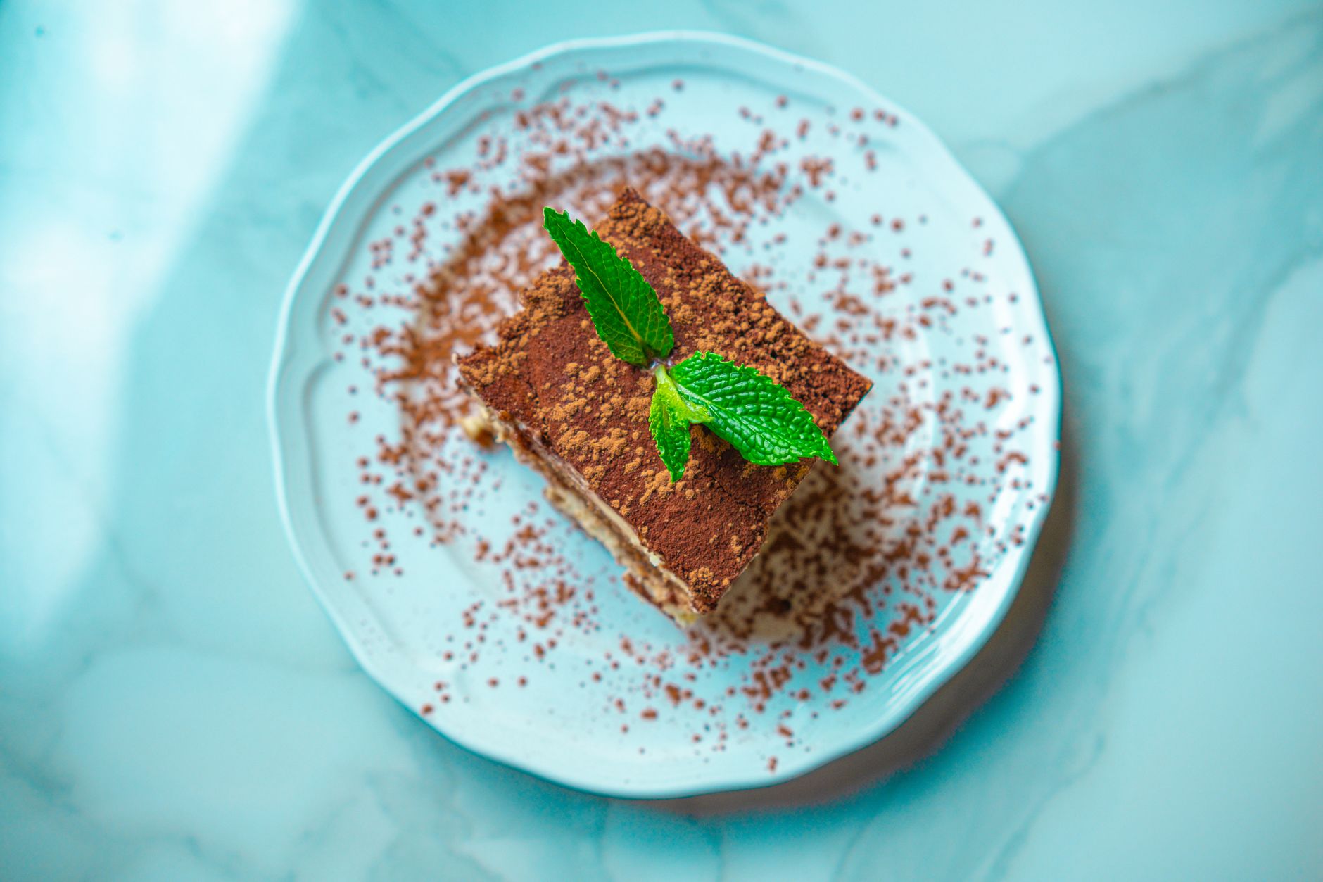 Tiramisù classico servito in un piatto con spolverata di cacao amaro