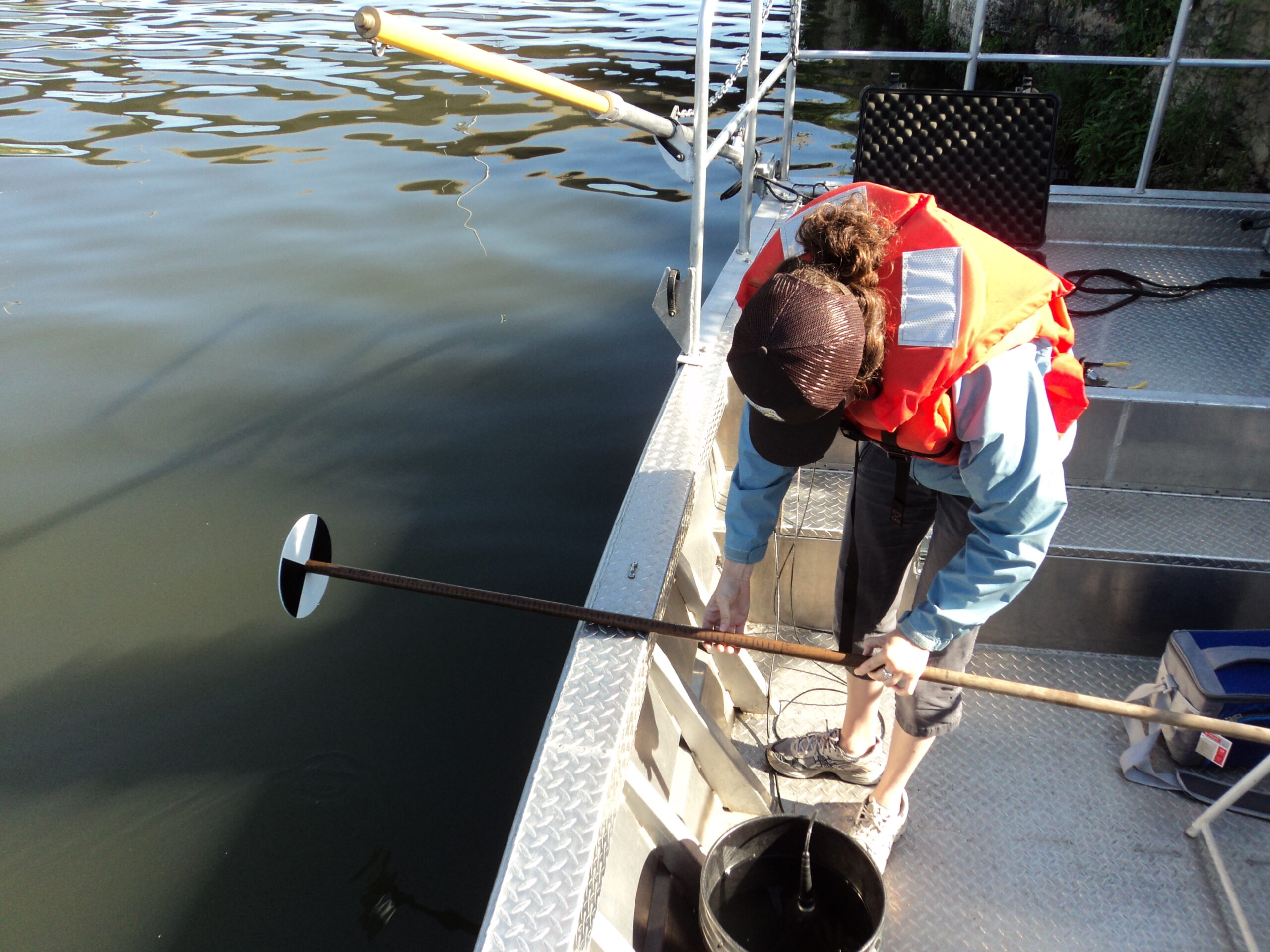 Un disco di Secchi bianco e nero calato in acqua da una barca per misurare la trasparenza