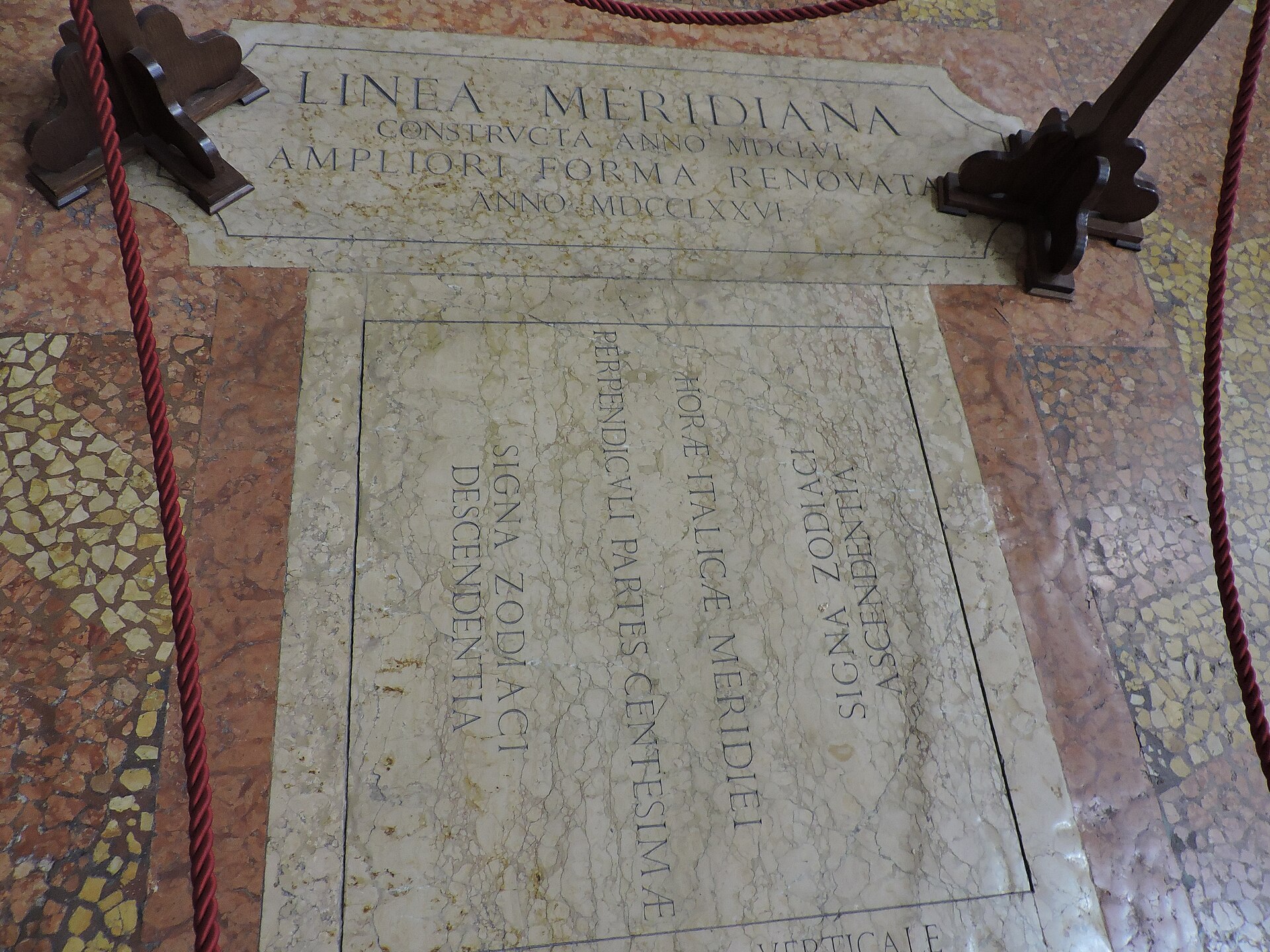 La lapide in marmo della linea meridiana nel pavimento della Basilica di San Petronio, con l'iscrizione latina e le date 1656 e 1776