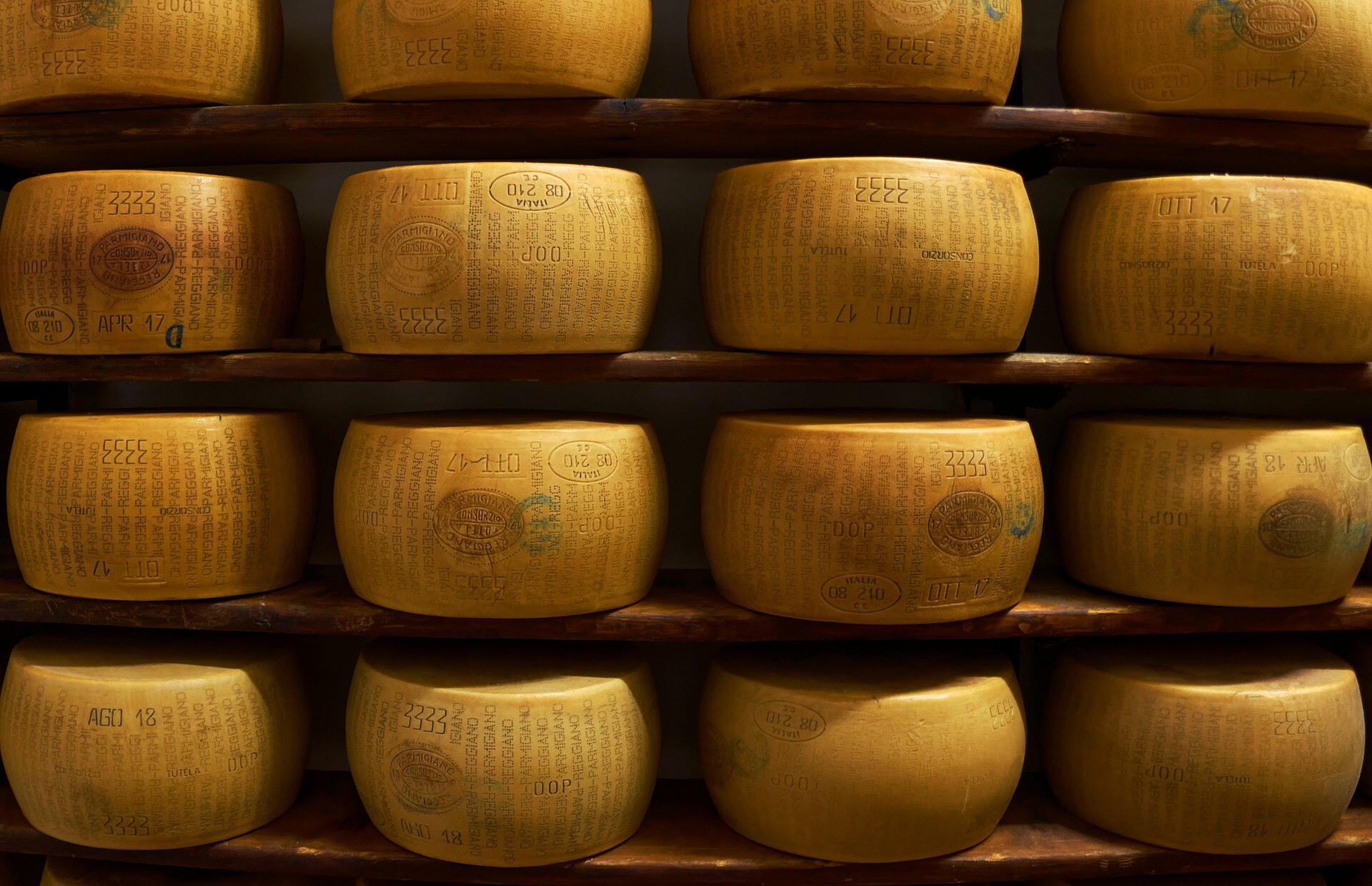 Forme di Parmigiano Reggiano su scaffali di legno in un magazzino di stagionatura