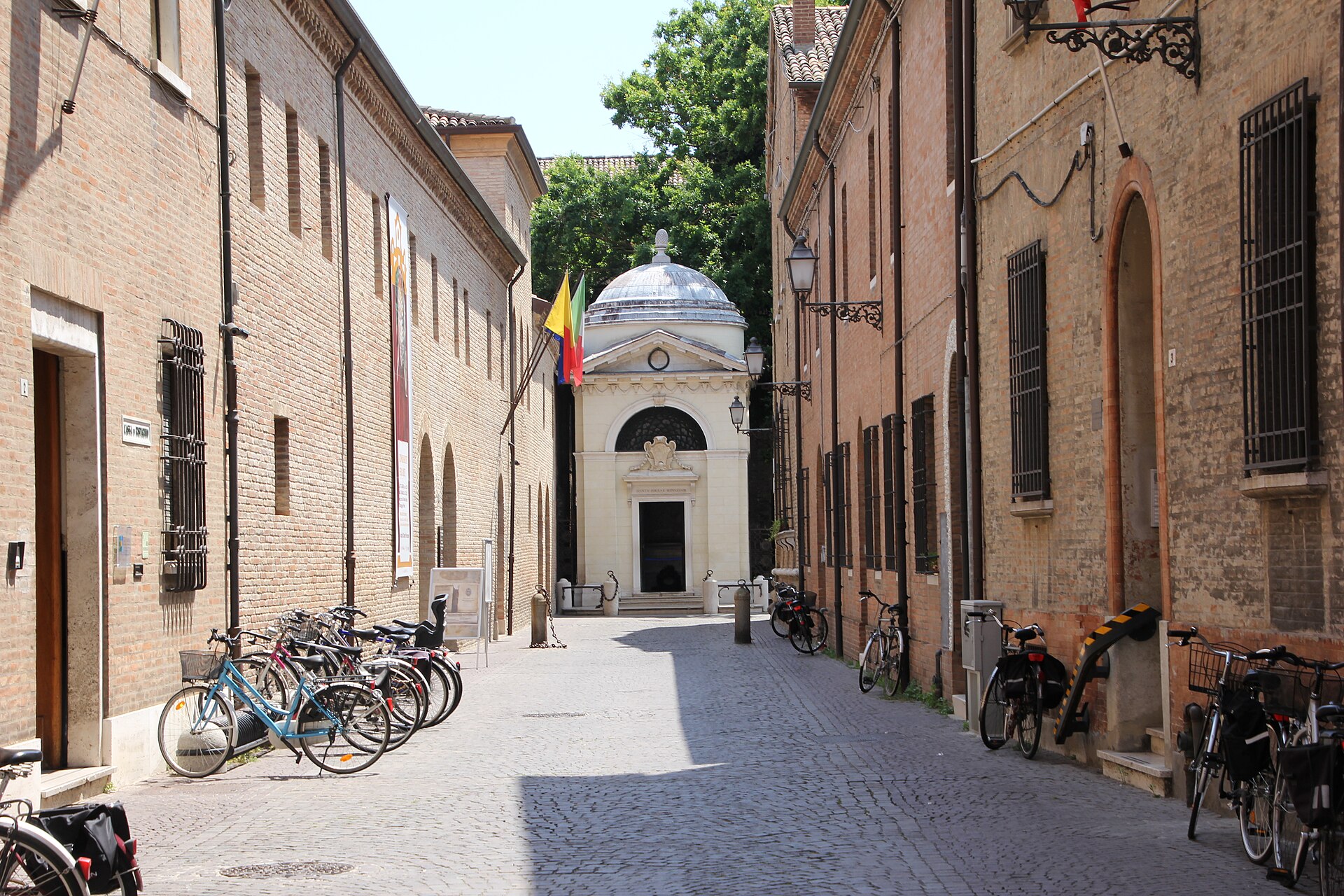 La via di Ravenna che porta al tempietto bianco della tomba di Dante, con biciclette lungo i muri di mattoni