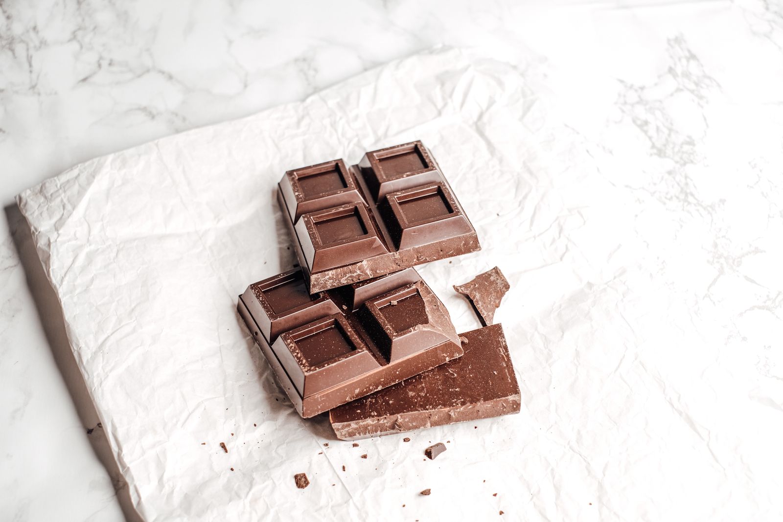 Una tavoletta di cioccolato fondente spezzata su carta stropicciata