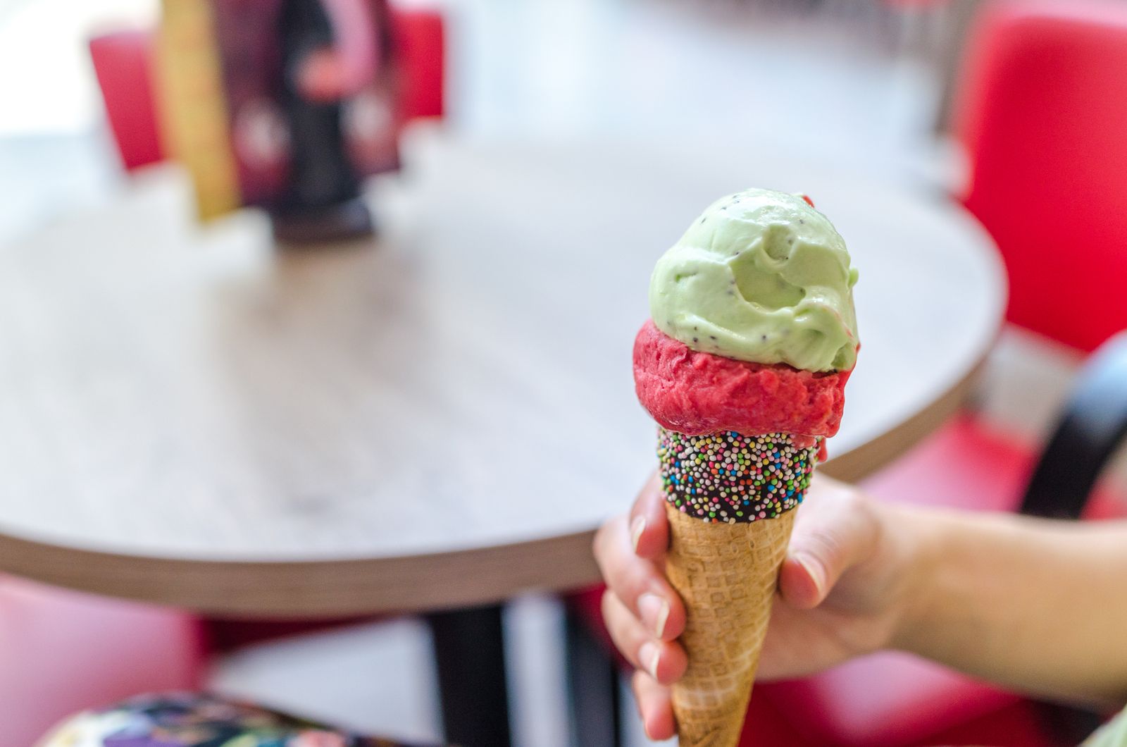 Una mano tiene un cono gelato colorato