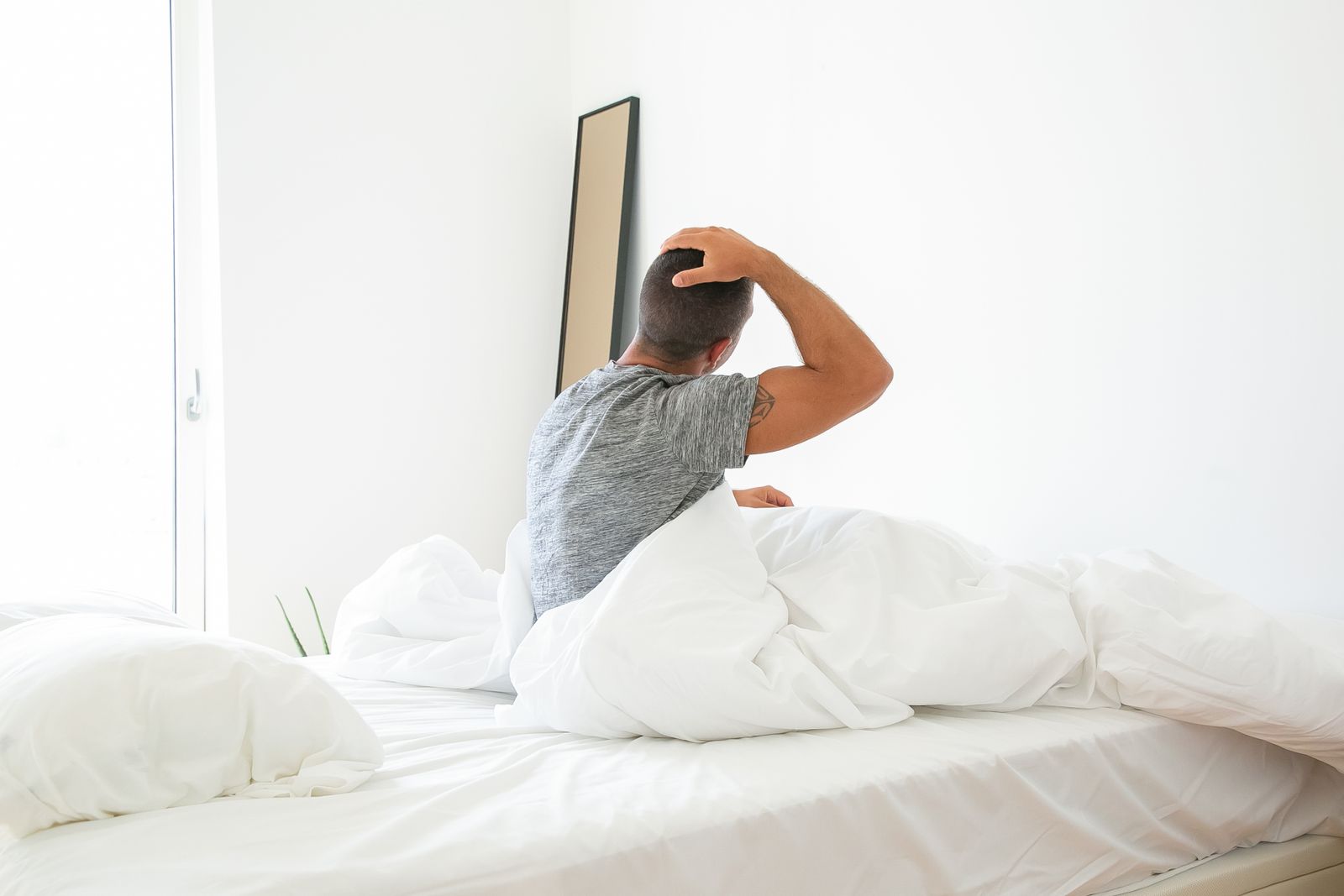 Uomo che si stiracchia nel letto appena sveglio, nella luce del mattino