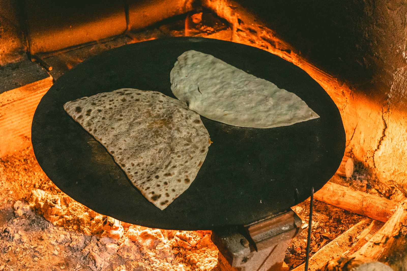 Pane piatto che cuoce su una piastra sopra il fuoco vivo