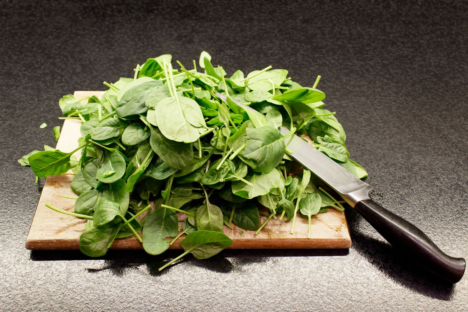 Foglie di spinaci freschi su un tagliere di legno