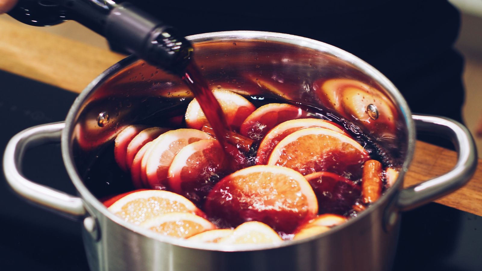 Vino rosso che scalda in una pentola con spezie e agrumi